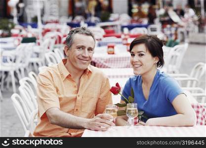 Portrait of a mature man and a young woman sitting together at a sidewalk cafe