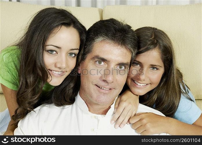 Portrait of a mature man and his two daughters smiling