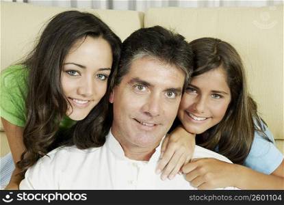Portrait of a mature man and his two daughters smiling