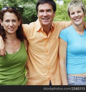 Portrait of a mature man and two mature women standing together and smiling