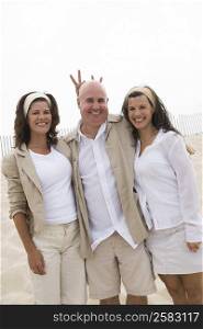 Portrait of a mature man and two mature women standing together on the beach