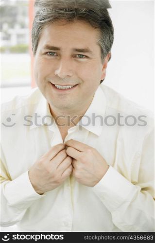 Portrait of a mature man buttoning his shirt and smiling