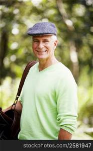 Portrait of a mature man carrying a golf bag and smiling