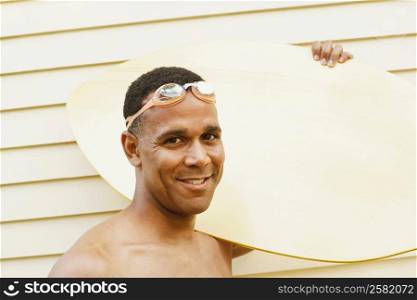 Portrait of a mature man carrying a surfboard and smiling
