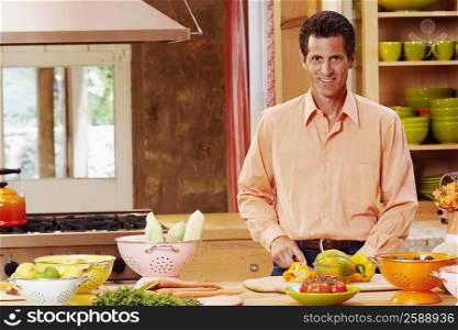 Portrait of a mature man cutting vegetables and smiling