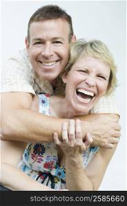 Portrait of a mature man embracing a mature woman from behind and smiling