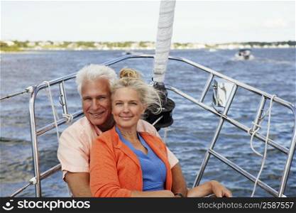 Portrait of a mature man embracing a mature woman from behind in a boat and smiling