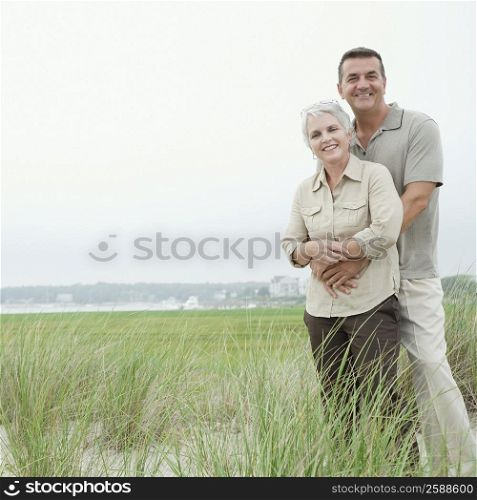 Portrait of a mature man embracing his wife from behind and smiling