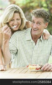 Portrait of a mature man feeding ice cream to a mature woman and smiling