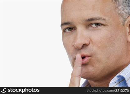 Portrait of a mature man gesturing with his finger on his lips
