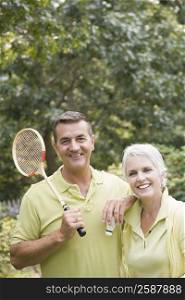 Portrait of a mature man holding a badminton racket and a shuttlecock beside his wife