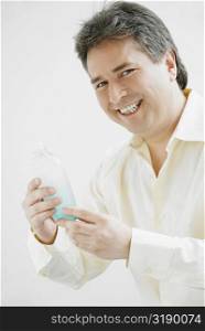 Portrait of a mature man holding a bottle of aftershave and smiling