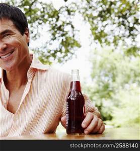 Portrait of a mature man holding a bottle of red wine and smiling
