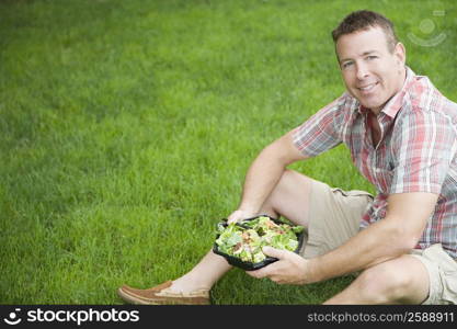 Portrait of a mature man holding a bowl of salad and smiling