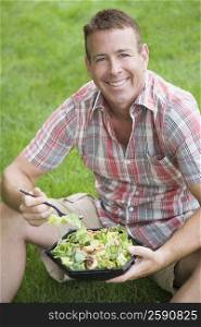 Portrait of a mature man holding a bowl of salad and smiling