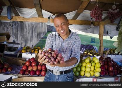 Portrait of a mature man holding a bunch of red grapes, Santo Domingo, Dominican Republic