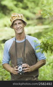 Portrait of a mature man holding a camera and smiling