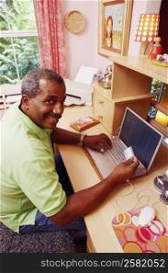Portrait of a mature man holding a credit card and using a laptop
