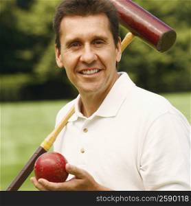 Portrait of a mature man holding a croquet mallet and a ball