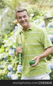 Portrait of a mature man holding a croquet mallet and a ball and smiling