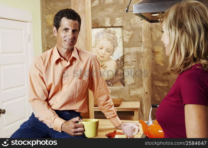 Portrait of a mature man holding a cup with a mature woman standing beside him