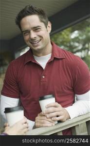 Portrait of a mature man holding a disposable cup and smiling