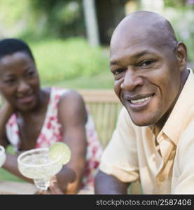 Portrait of a mature man holding a glass of cocktail and smiling