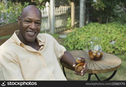 Portrait of a mature man holding a glass of ice tea and smiling