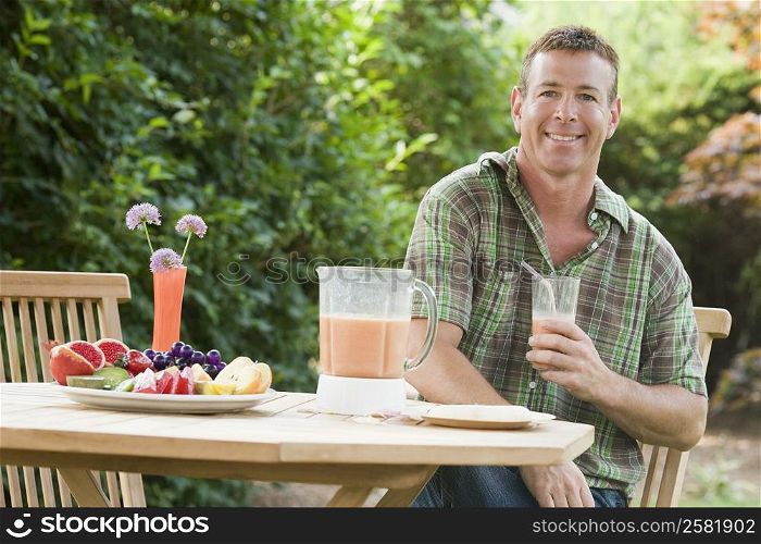 Portrait of a mature man holding a glass of juice and smiling