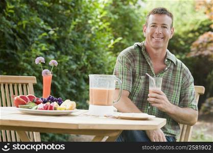 Portrait of a mature man holding a glass of juice and smiling