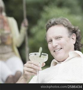 Portrait of a mature man holding a glass of martini and smiling