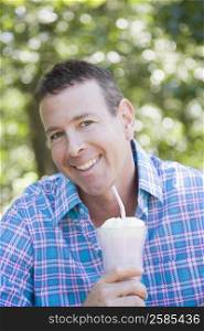 Portrait of a mature man holding a glass of milkshake