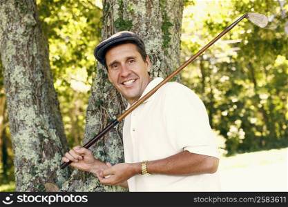 Portrait of a mature man holding a golf club and a golf ball