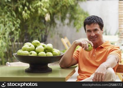 Portrait of a mature man holding a granny smith apple and smiling