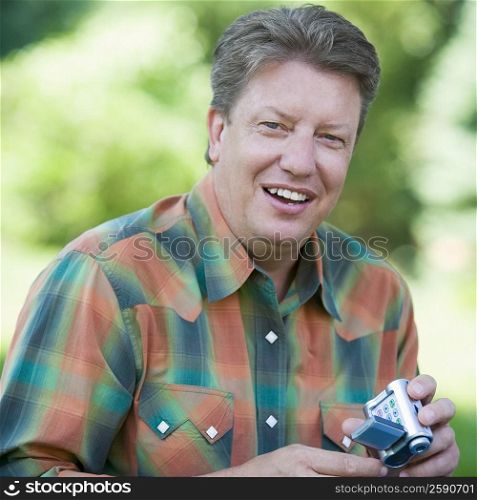 Portrait of a mature man holding a home video camera and smiling