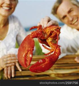 Portrait of a mature man holding a lobster with a mature man beside him