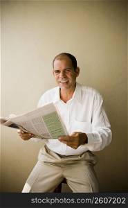Portrait of a mature man holding a newspaper and smiling