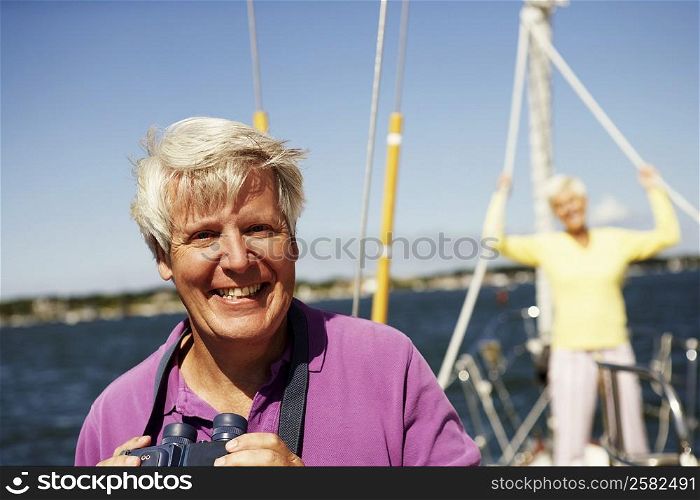 Portrait of a mature man holding a pair of binoculars in a boat with a mature woman standing behind him