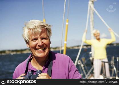 Portrait of a mature man holding a pair of binoculars in a boat with a mature woman standing behind him