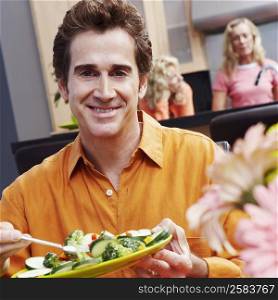 Portrait of a mature man holding a plate of salad and smiling