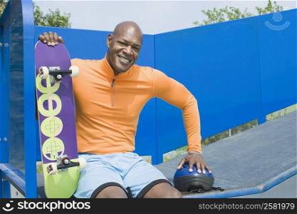 Portrait of a mature man holding a skateboard and smiling