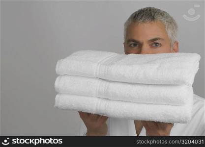 Portrait of a mature man holding a stack of folded towels