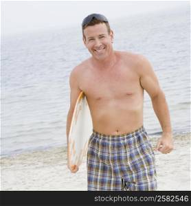 Portrait of a mature man holding a surfboard and smiling