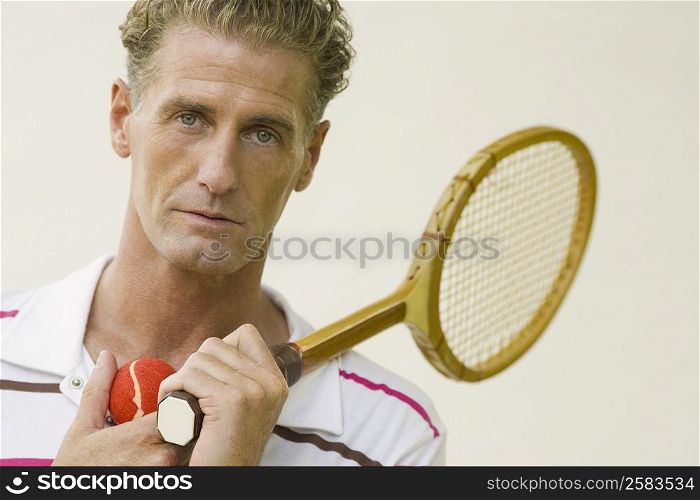 Portrait of a mature man holding a tennis racket and a tennis ball