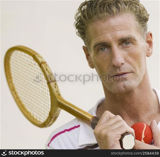 Portrait of a mature man holding a tennis racket and a tennis ball
