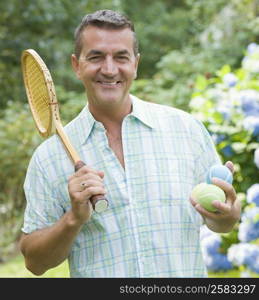 Portrait of a mature man holding a tennis racket and balls