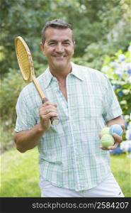 Portrait of a mature man holding a tennis racket and balls