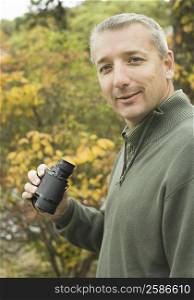 Portrait of a mature man holding binoculars and smiling