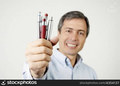 Portrait of a mature man holding pens and smiling