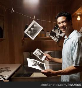 Portrait of a mature man holding photographs in a dark room